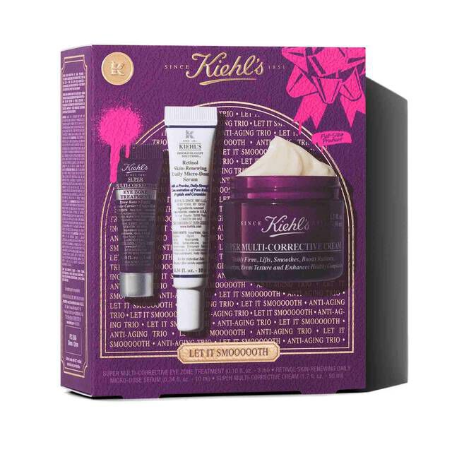 A graphic featuring a purple Kiehl’s gift box with gold accents. The box contains three products: a small purple tube of "Kiehl's Super Multi-Corrective Eye Zone Treatment," a white and purple tube of "Kiehl's Retinol Skin-Renewing Daily Micro-Dose Serum," and a purple jar of "Kiehl's Super Multi-Corrective Cream" with visible cream. The box is decorated with bright pink graphic paint splatters and a bow design, and features the text "LET IT SMOOOOOTH" at the bottom.
