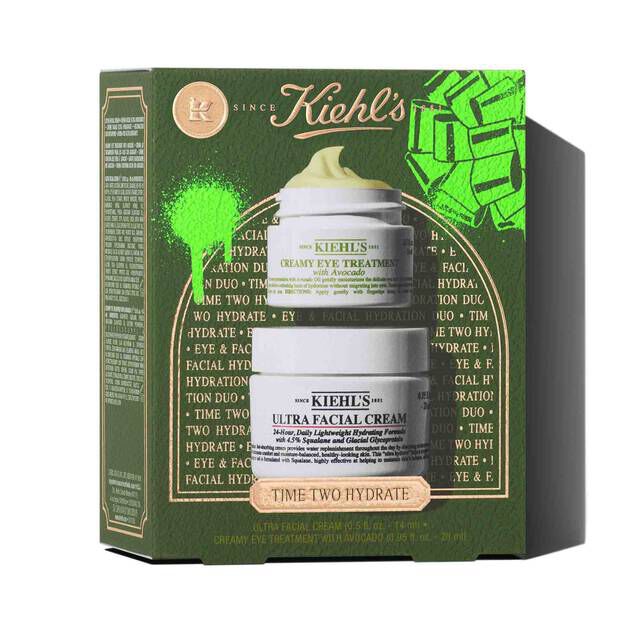 Two white jars of Kiehl's products are stacked vertically. The top jar is "KIEHL'S CREAMY EYE TREATMENT with Avocado" showing a yellow-green swirl of product on top. The bottom jar is "KIEHL'S ULTRA FACIAL CREAM". Both jars are casting shadows on a white background.